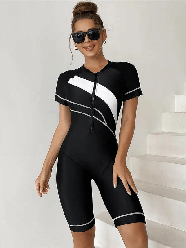 Stylish woman wearing a black and white one-piece beach sports swimsuit with zipper, perfect for swimming or sunny beach activities.
